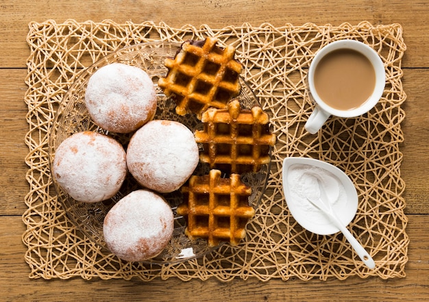 Bovenaanzicht van donuts met poedersuiker en wafels