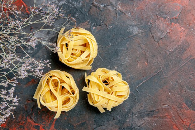 Bovenaanzicht van drie ongekookte spaggeties op tafel met gemengde kleuren