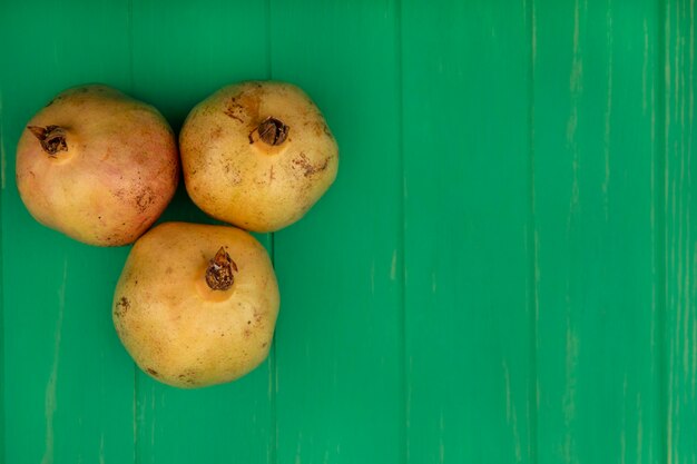 Bovenaanzicht van drie zoete granaatappels geïsoleerd op een groene houten muur met kopie ruimte