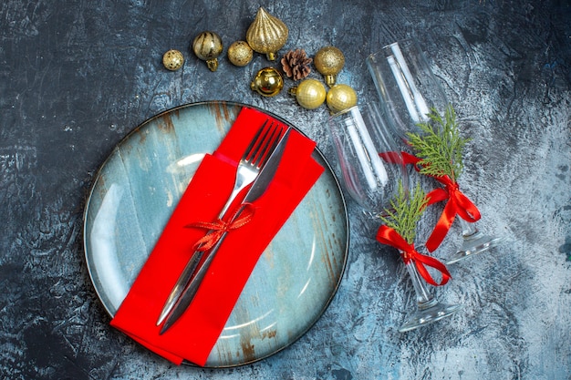 Bovenaanzicht van een bestekset op een blauw bord en gevallen glazen bekers naast decoratieaccessoires op een donkere achtergrond