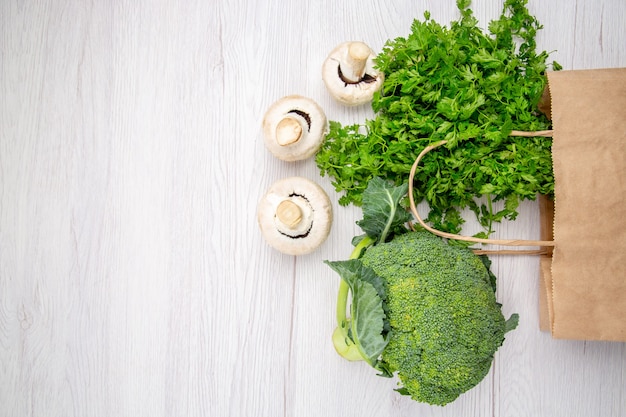 Bovenaanzicht van een bundel verse groene champignons broccoli in een mand aan de linkerkant op een witte achtergrond