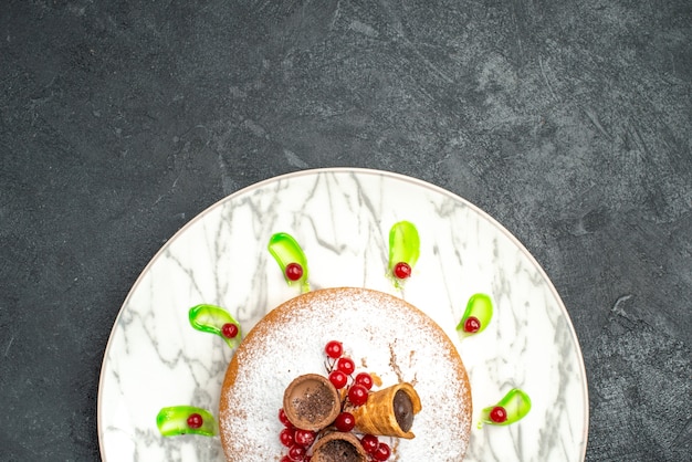 Bovenaanzicht van een close-up een cake grijze plaat van een cake met groene saus bessen poedersuiker