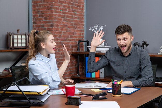 Bovenaanzicht van een gelukkig en glimlachend managementteam dat aan tafel zat, kwam tot onderhandeling in de vergaderruimte op kantoor