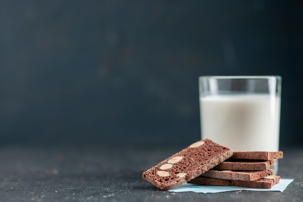 Bovenaanzicht van een glas melk en chocoladekoekjes aan de linkerkant op een zwarte ondergrond
