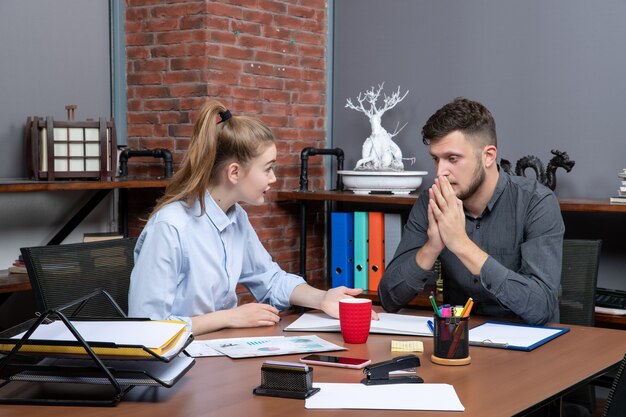 Bovenaanzicht van een jonge vrouw die aan een tafel zit en haar collega op kantoor motiveert