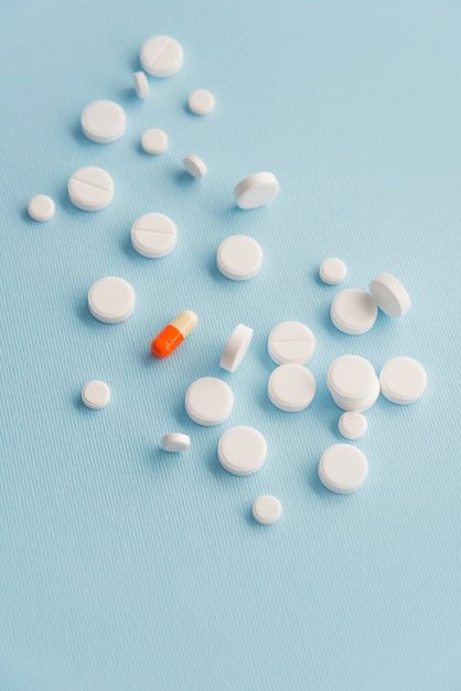 Bovenaanzicht van een kleurrijke pil omgeven door witte pillen