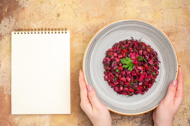 Bovenaanzicht van een kom met een rode salade met groenten erop op een houten backgorund