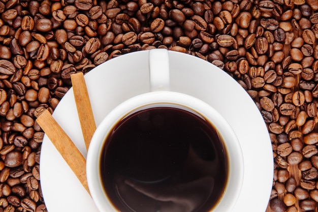 Bovenaanzicht van een kopje koffie met krokante stokken op koffiebonen achtergrond