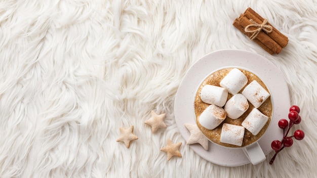 Bovenaanzicht van een kopje warme chocolademelk met marshmallows en kaneelstokjes