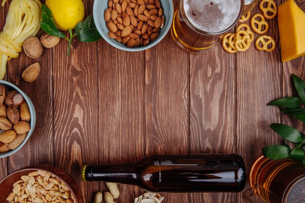 Bovenaanzicht van een mok bier met verschillende zoute snacks op rustiek hout met kopie ruimte