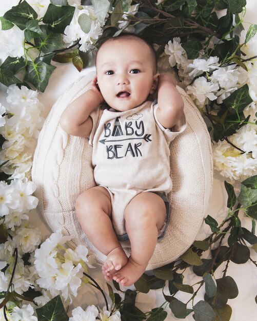 Bovenaanzicht van een schattige babyjongen in een mand omringd door bloemen