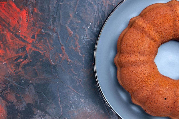 Bovenaanzicht van een smakelijke taart blauwe plaat van een taart op de donkere tafel