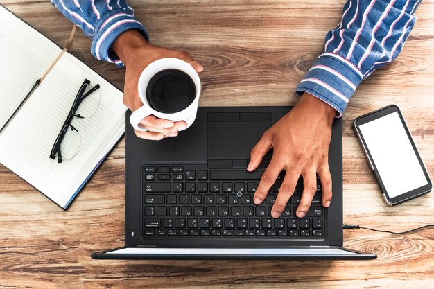 Bovenaanzicht van een zakenman die koffie drinkt en aan een project werkt