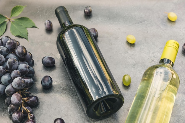 Bovenaanzicht van fles rode en witte wijn groene wijnstok wijnglas en rijpe druif op vintage donkere stenen tafel...