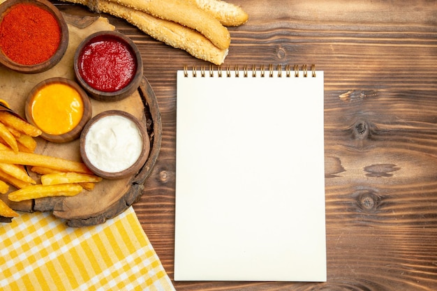 Bovenaanzicht van frietjes met brood en kruiden op bruin houten tafel fastfood maaltijd aardappel peper pittig