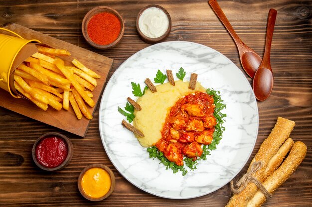 Bovenaanzicht van frietjes met plakjes kip op bruine tafel