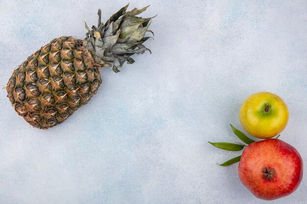 Bovenaanzicht van fruit als ananas, granaatappel en appel op witte ondergrond