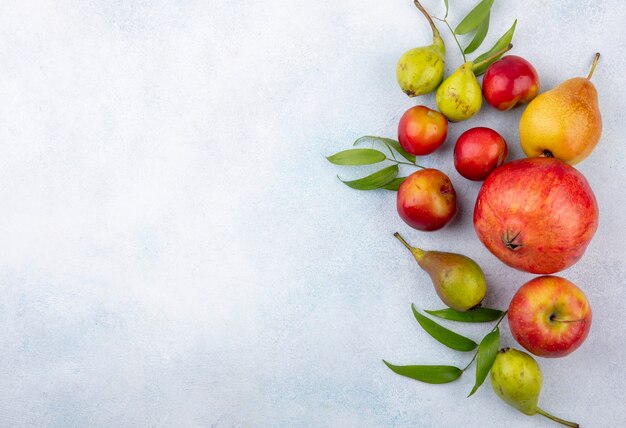 Bovenaanzicht van fruit als pruim appel perzik en granaatappel op witte ondergrond