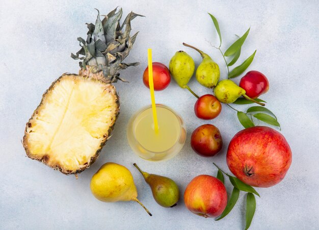 Bovenaanzicht van fruit met ananassap op witte ondergrond