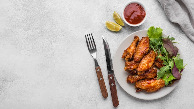 Bovenaanzicht van gebakken kip op plaat met salade en saus