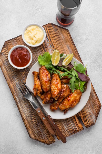 Bovenaanzicht van gebakken kip op plaat met saus en koolzuurhoudende drank