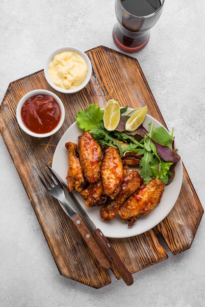 Bovenaanzicht van gebakken kip op plaat met saus en koolzuurhoudende drank