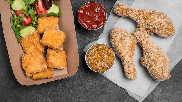 Bovenaanzicht van gebakken kipnuggets met sauzen en salade