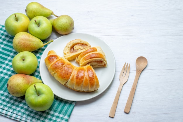 Bovenaanzicht van gebakken lekker gebak armband gevormd in glas gesneden plaat samen met appels en peren op wit, gebak koekjes zoet koekje