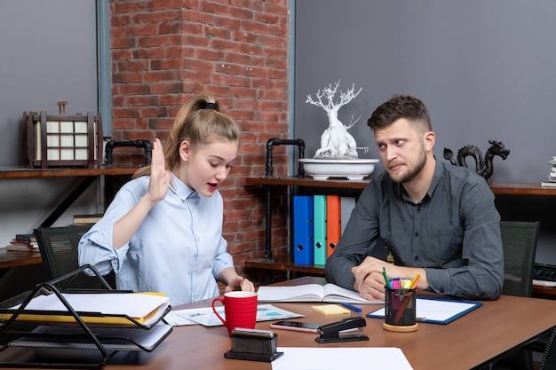 Bovenaanzicht van geconcentreerd en druk managementteam dat aan tafel zit en één onderwerp op kantoor bespreekt