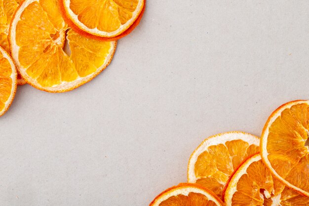 Bovenaanzicht van gedroogde stukjes sinaasappel gerangschikt op witte achtergrond met kopie ruimte