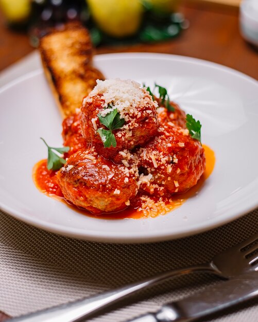 Bovenaanzicht van gehaktballen plaat gegarneerd met tomatensaus geraspte parmezaanse kaas en peterselie