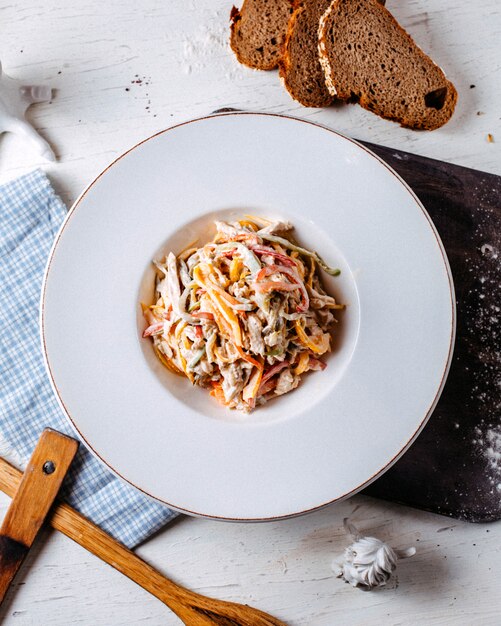 Bovenaanzicht van gehakte en fijngehakte kip champignonsalade met kleurrijke paprika in een bord