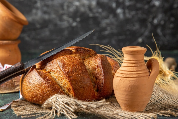 Bovenaanzicht van geheel zwart brood op bruine handdoekpotteries op donkere muur