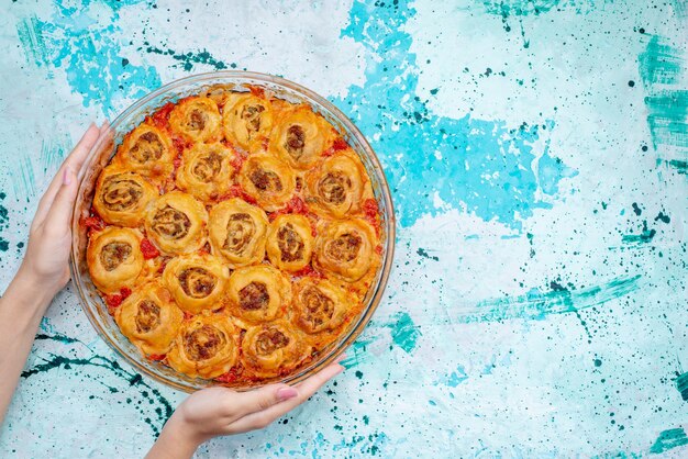 Bovenaanzicht van gekookte deegmaaltijd met gehakt en tomatensaus in glazen pan op helder bureau, bak voedsel vleesdeeg