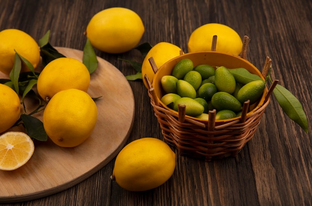 Bovenaanzicht van gele geschilde citroenen geïsoleerd op een houten keukenbord met kinkans op een emmer op een houten muur