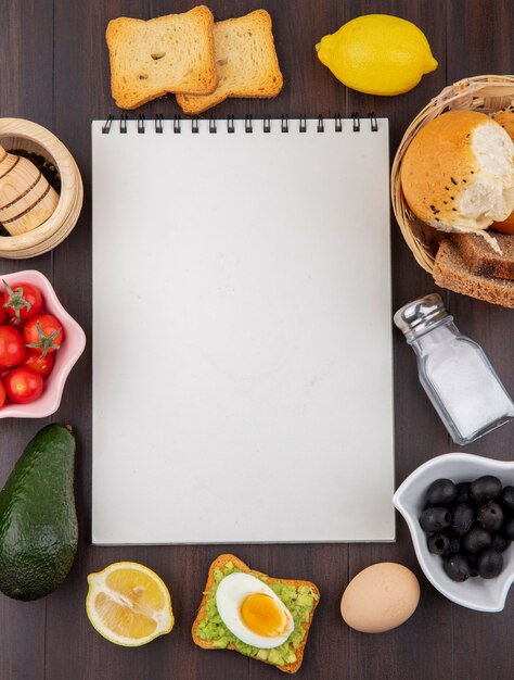 Bovenaanzicht van geroosterde sneetjes brood met citroen met een emmer van verschillende soorten brood tomaten op houten oppervlak