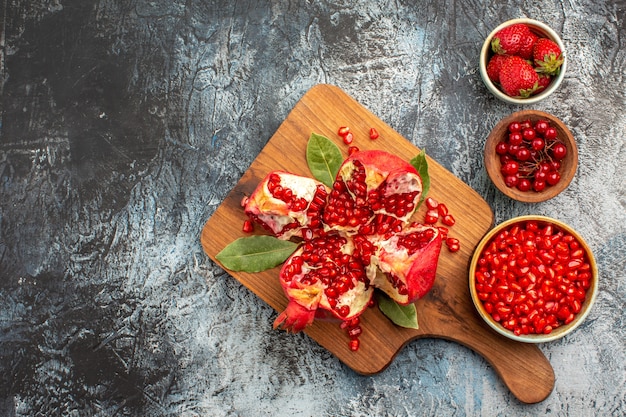 Bovenaanzicht van gesneden granaatappels met rood fruit op een donkere achtergrond boom vers fruit