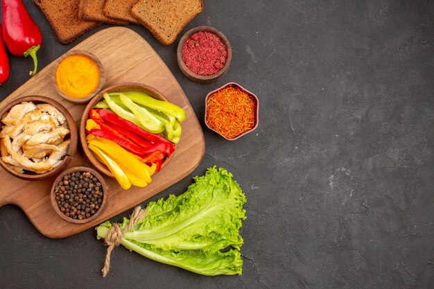 Bovenaanzicht van gesneden paprika met kruiden en brood op zwart