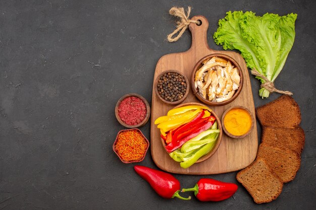 Bovenaanzicht van gesneden paprika met kruiden en donker brood op zwart