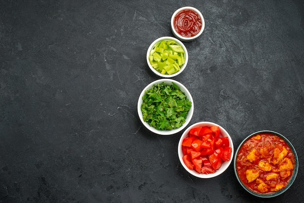 Bovenaanzicht van gesneden rode tomaten met groen op grijs