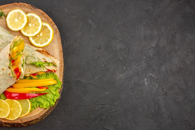 Bovenaanzicht van gesneden shaurma heerlijke vleessandwich met schijfjes citroen op zwart