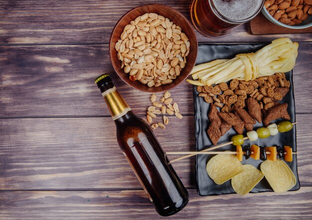 Bovenaanzicht van gevarieerd bier snacks met een flesje bier op rustieke met kopie ruimte