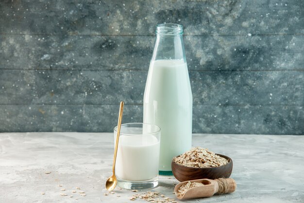 Bovenaanzicht van glazen beker en fles gevuld met melk en haver binnen buiten de bruine pot op grijze achtergrond