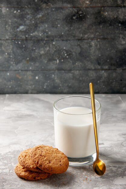 Bovenaanzicht van glazen beker gevuld met melk en gouden lepelkoekjes op grijze tafel op donkere achtergrond met vrije ruimte