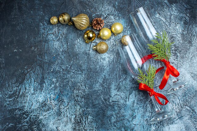 Bovenaanzicht van glazen bekers met rood lint en decoratieaccessoires aan de linkerkant op donkere achtergrond