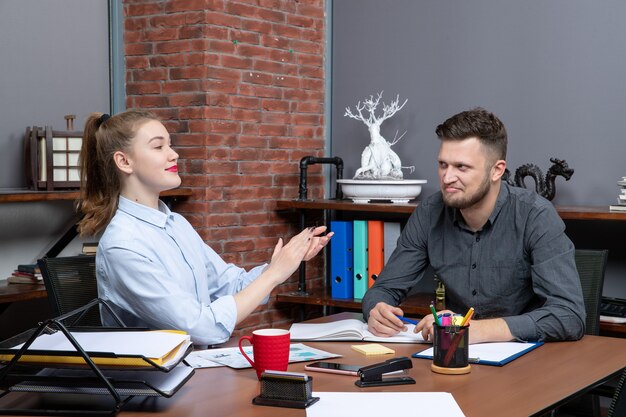 Bovenaanzicht van glimlachend en tevreden managementteam dat aan tafel zit en één onderwerp bespreekt in de vergaderruimte op kantoor