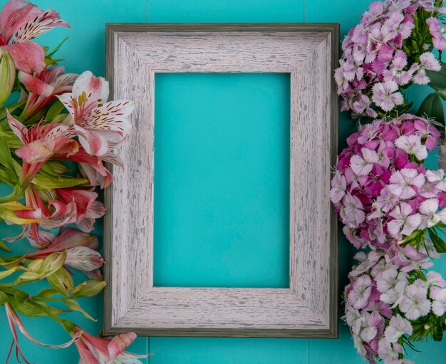 Bovenaanzicht van grijs frame met lichtpaarse bloemen en roze lelies op een lichtblauw oppervlak