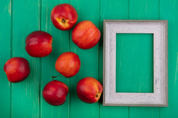 Gratis foto bovenaanzicht van grijs frame met perziken op een groen oppervlak