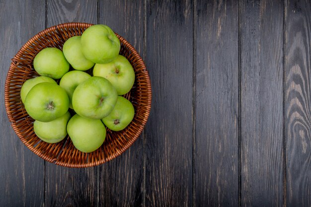 Bovenaanzicht van groene appels in mand op houten achtergrond met kopie ruimte