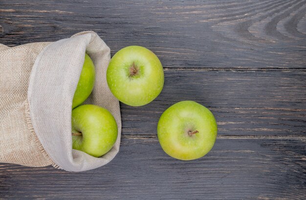 bovenaanzicht van groene appels morsen uit zak op houten achtergrond